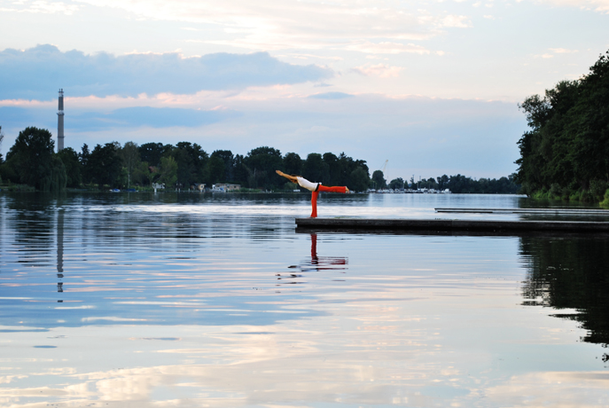 Yogalehrerin Birgit Braune in der Yogahaltung des Kriegers 3 auf einem Steg am Wasser